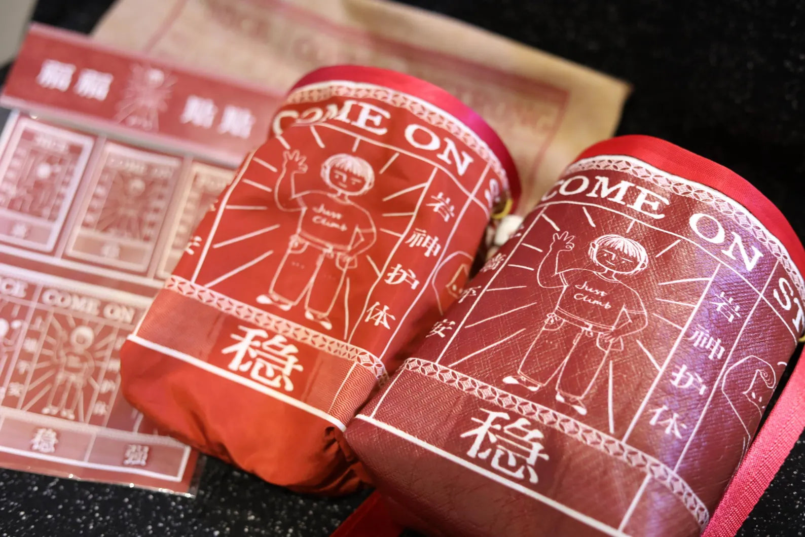 Red rock climbing chalk bags with the words "Nice, Come On, and Strong" and the cartoon style illustration of a confident climber