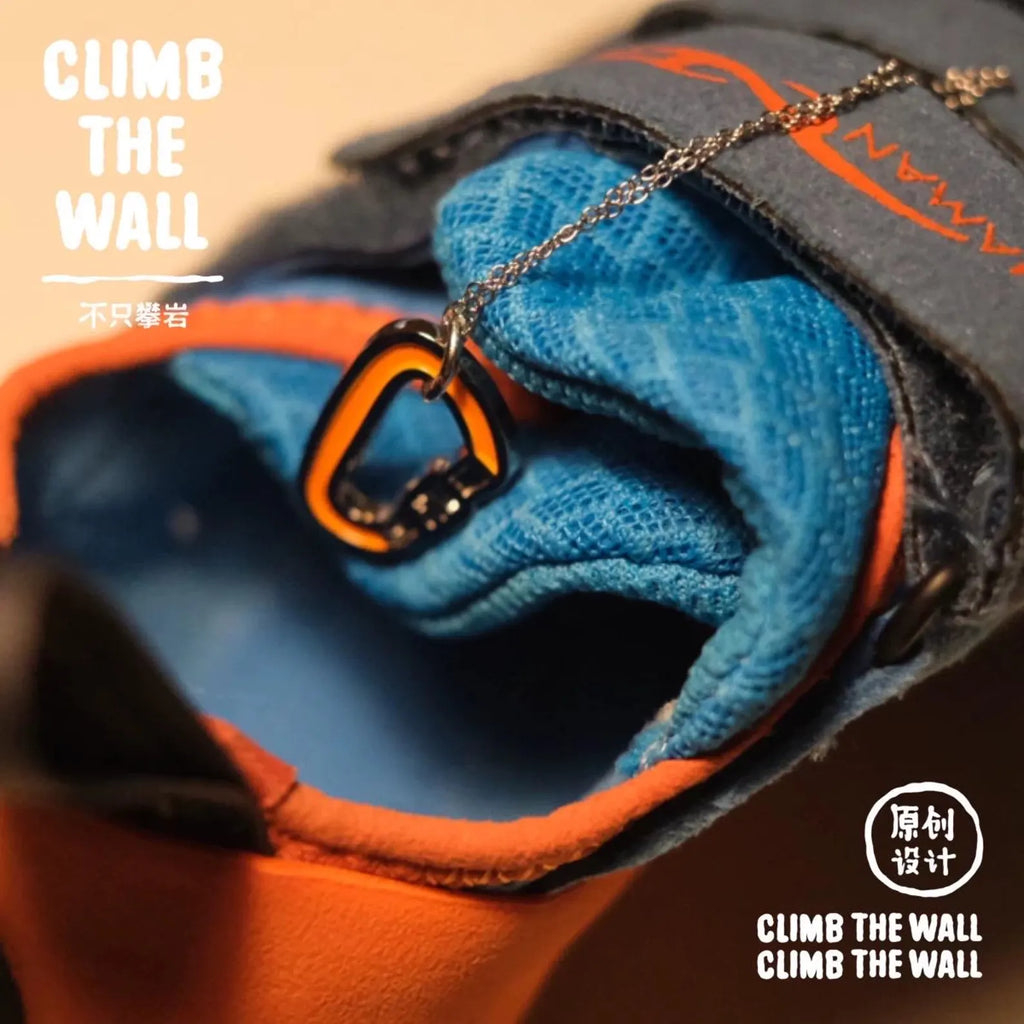 Close-up of climbing shoes with blue socks and orange carabiner, featuring 'Climb the Wall' branding.