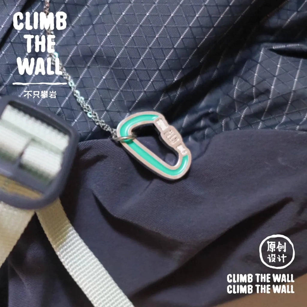Close-up of a climbing carabiner and rope on dark fabric with 'CLIMB THE WALL' branding.